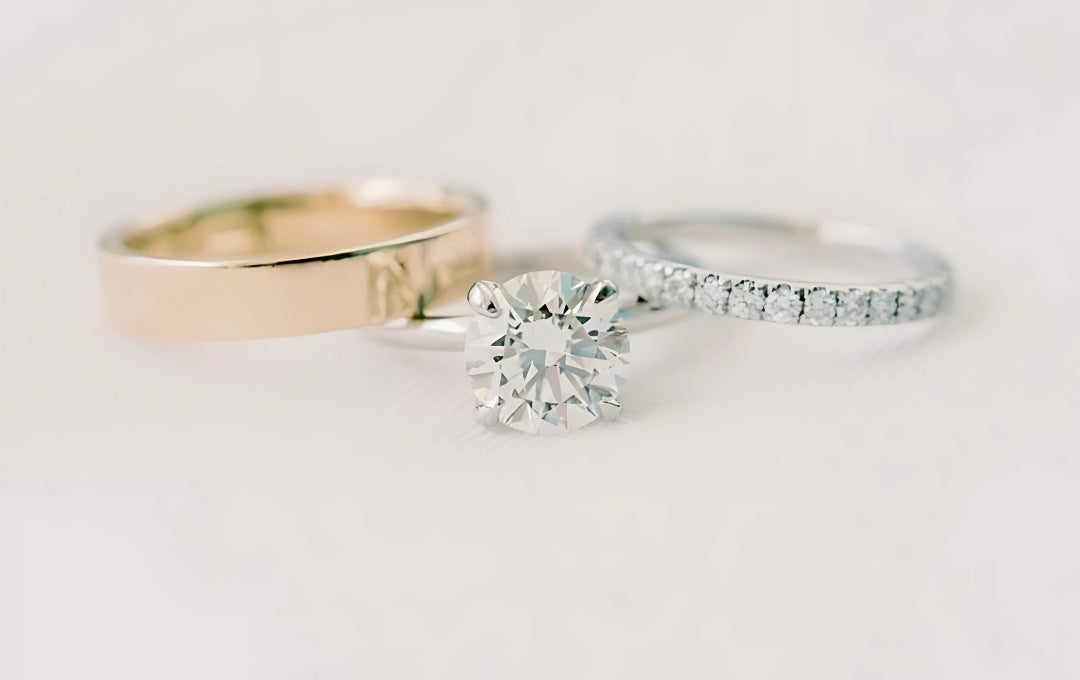Two diamond rings, one gold and one silver, on a light gray background.