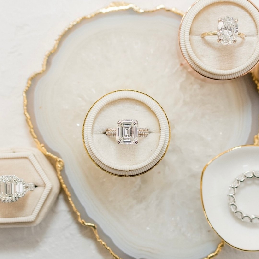 Three diamond engagement rings, and emerald cut, asscher shape and oval diamonds in jewelry boxes. 
