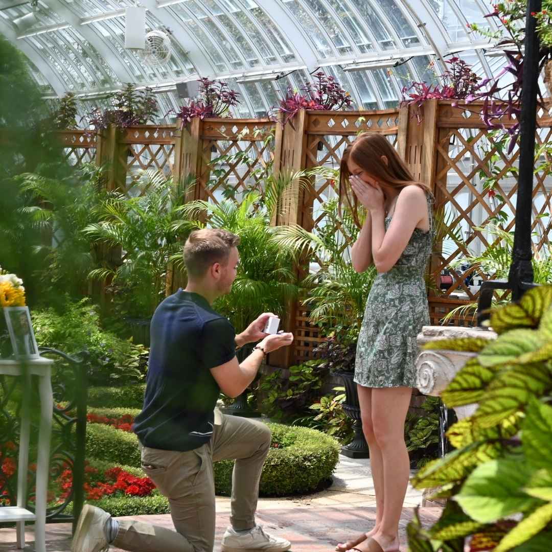 Man proposing to a woman in a greenhouse setting