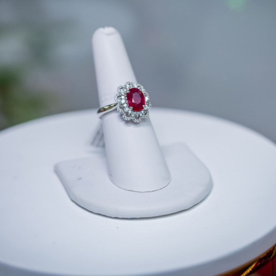 White Gold ring with a ruby center stone and diamond halo on a white stand